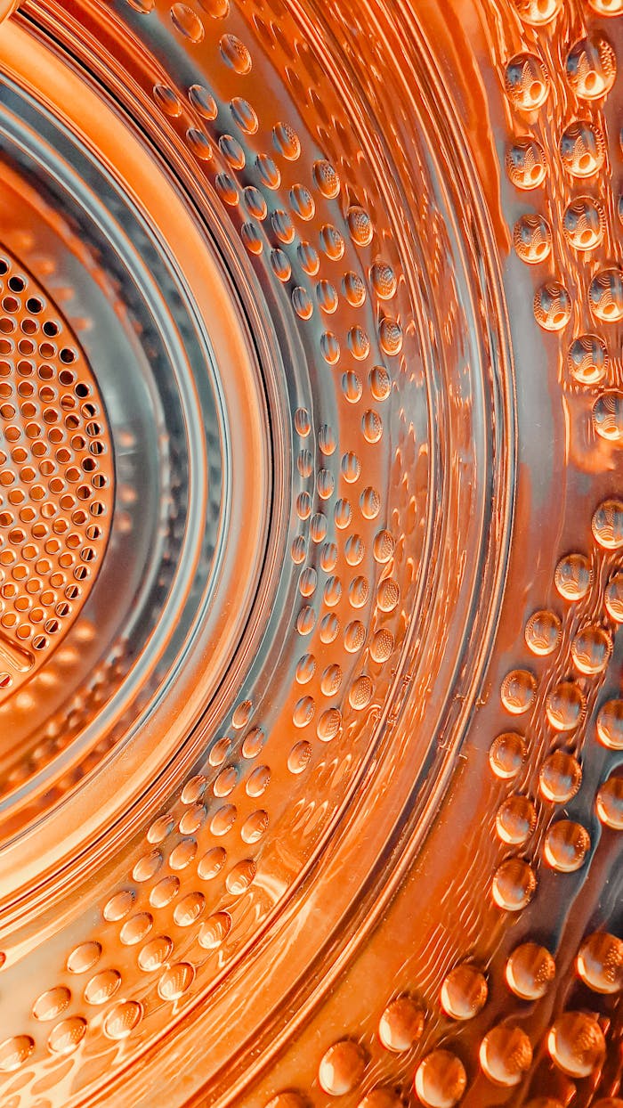 about-us-01 Dynamic close-up of a washing machine drum with vibrant orange lighting and textures.